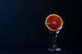 Grapefruit in a martini glass on a black background.