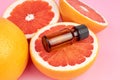 Grapefruit pure essential oil with fresh grapefruit halves on pink background.