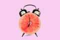 Grapefruit slice on alarm clock, pink pastel background. fruit and vitamins diet nutrition concept