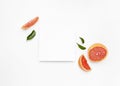 Grapefruit slices surrounding a blank piece of paper isolated on a white background Royalty Free Stock Photo