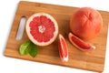 Grapefruit whole and sliced with leaves on a cutting wooden board,isolated on a white background.