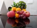 Grapes, apples, oranges, floral with white background and reflection on a glass table. Royalty Free Stock Photo