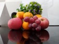 Grapes, apples, oranges, floral with white background and reflection on a glass table. Royalty Free Stock Photo
