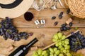 Grapes, bottle of wine, glass with wine, hat on a wooden background. View from above. Winemaking and harvesting concept