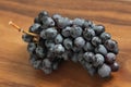 Grapes. A bunch of dark, black grapes lies on a wooden board close-up