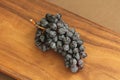 Grapes. A bunch of dark, black grapes lies on a wooden board close-up