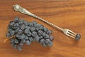 Grapes. A bunch of dark, black grapes lies on a wooden board close-up and a vintage fork