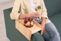 Grapes and cheese on sofa armrest wooden table. Woman holding glass of wine at home, closeup