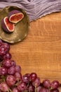 Flatlay with grapes, figs, drapery, copper saucer on a wooden board.