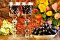 Grapes are a delicious delicacy and wine in a glass on the background of garden flowers and bokeh lights holiday. Wine in glasses