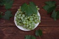 Grapes, green leaves on a wooden background