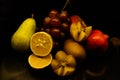 Grapes Kiwi Pear Plum Pomegranate summery fruits on black background with it`s reflection juicy fresh