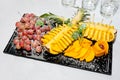 Grapes, pineapple and persimmon are beautifully served on a porcelain platter