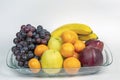 Grapes, red and green apples, tangerines and bananas on a transparent plate. Ripe fruits on a transparent plate