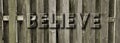 Graphic Background of Text BELIEVE engraved in Wood Fence