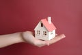 Hand with a wooden house resting on its palm.