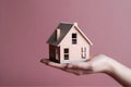 Hand with a wooden house resting on its palm.