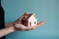 Hand with a wooden house resting on its palm.