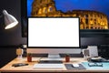 Graphic designer`s workspace with a pen tablet, a computer and white backgroud for text with view of colosseum from the window Royalty Free Stock Photo