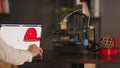 A graphic designer uses a laptop and makes a sketch of human heart in red colour, depicted on a device monitor. The