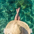 Graphic image of top down view of woman wearing big summer sun hat relaxing on small wooden pier by clear turquoise sea Royalty Free Stock Photo