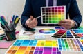 Graphic or interior young designer in suit choosing color from swatch sample or catalogue palette guide at workplace. graphic Royalty Free Stock Photo