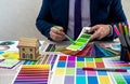 Graphic or interior young designer in suit choosing color from swatch sample or catalogue palette guide at workplace. graphic Royalty Free Stock Photo