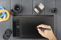 Graphic tablet for graphic design with white human hand and pen on gray wood with photographic camera lenses and color filters Royalty Free Stock Photo