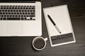 Graphics tablet with a pencil, laptop keyboard and cup of coffee on a black wooden table, close up Royalty Free Stock Photo