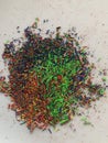 Graphite shavings of multiple colors and shades with poignant green spread on a white background