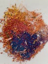 Graphite shavings of yellow red blue and violet spread in abstract circular form slightly intermixed