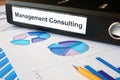 Graphs and file folder with label Management Consulting.