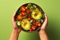 Grasping a Bowl Laden with Nutrient-Rich Greens, Including Avocado, Tomato, and a Variety of Healthy Vegetables