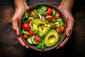 Grasping a Bowl Laden with a Wholesome Salad, Highlighting Avocado, Tomato, and a Medley of Nutrient-Rich Vegetables