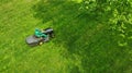 Lawn mower with gardener. Grass cutting. Aerial from drone.