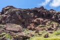 Grass, daisies and red rocks on a summer sunny day. Road to the red beach, Santorini island, Greece Royalty Free Stock Photo