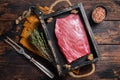 Grass Fed raw flank beef meat steak in wooden tray with herbs. Wooden background. Top view Royalty Free Stock Photo