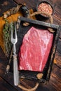 Grass Fed raw flank beef meat steak in wooden tray with herbs. Wooden background. Top view Royalty Free Stock Photo