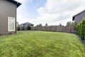 Grass filled back yard. Brown siding house exterior