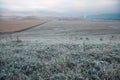 Grass with frost in a field at dawn. Dawn in autumn field. Hills in morning haze. Grass covered with autumn hoarfrost. Royalty Free Stock Photo