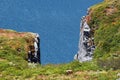 Grass green rocky cliff against blue water background Royalty Free Stock Photo