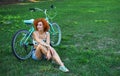 Shot of young woman relaxing on the grass while out for bike ride in the countryside