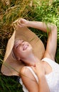 Grass, hat and woman relax on lawn with peace, happiness and freedom in summer. Outdoor, fashion and girl lying in field