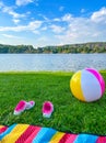 Grass river beach in the Czech Republic, beach ball, picnic mat and pink sneakers on a sunny day Royalty Free Stock Photo