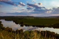 Grass at sunset, darkness on opposite bank of river Dniester, state border with Moldova, still water surface with clouds and trees