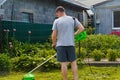 Grass trimmer. Back view of a man mowing the grass. Outdoor view of young worker using a lawn trimmer mower cutting Royalty Free Stock Photo