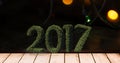 2017 in grass on wooden plank against a composite image 3D of christmas lights Royalty Free Stock Photo