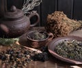 Grasses are dry, grasses on the table and ceramic dishes, clay Chinese kettle and herbs are different on a wooden background