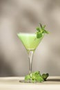 Grasshopper green alcoholic cocktail drink with mint liqueur, cream, ice and fresh mint. Beige background, hard light, shadow
