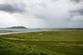 Grasslands and lakes with mountains behind under cloudy skies